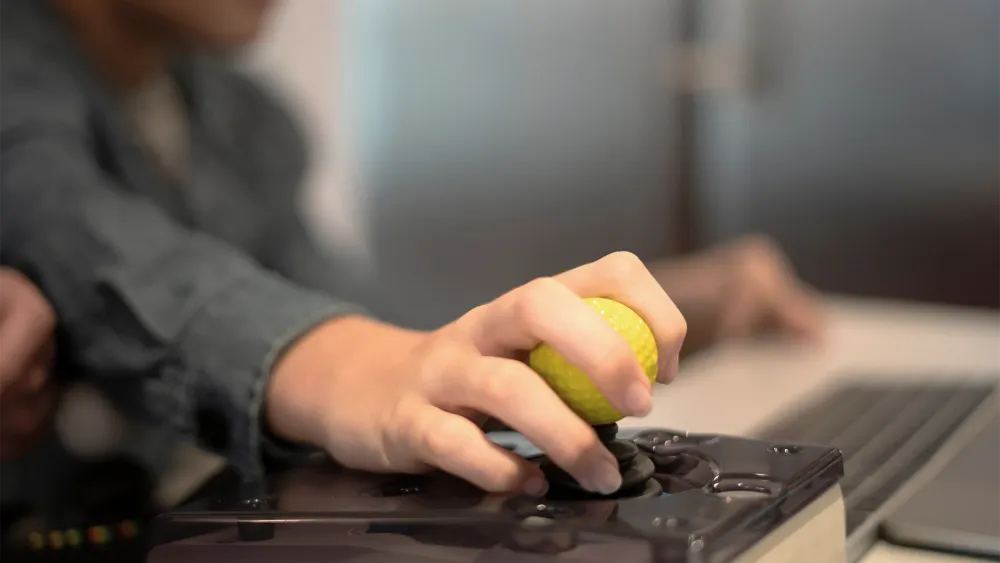 Person sitzt an einem Screenreader, Finger auf einer Tastatur