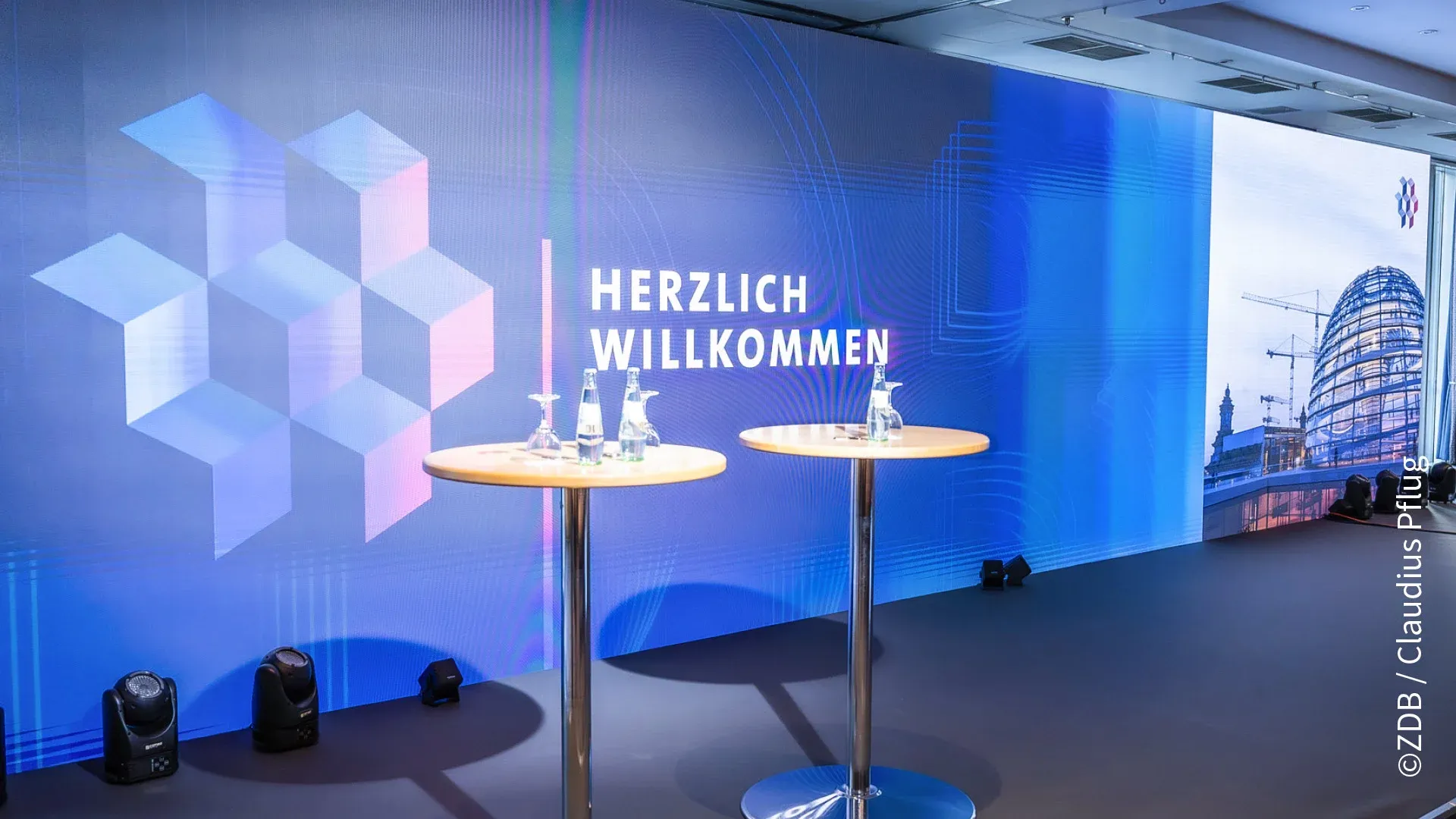 Bühnenrückwand mit dem Logo, dem Text Herzlch Wollkommen und der Reicstagskuppel