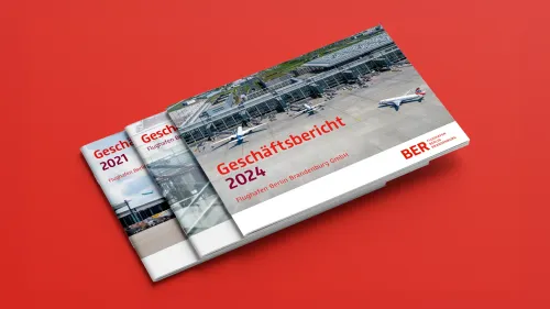 Drei Berichte im Querformat liegen übereinander auf roten Hintergrund. Es handelt sich um die Jahresberichte für den Flughafen Berlin-Brandenburg/FBB
